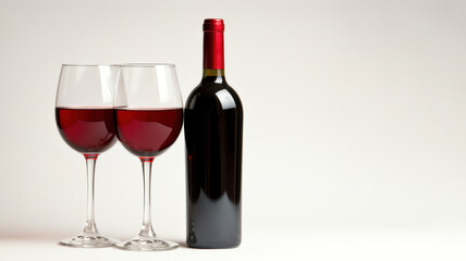 A bottle of red wine and two glasses on a white background.