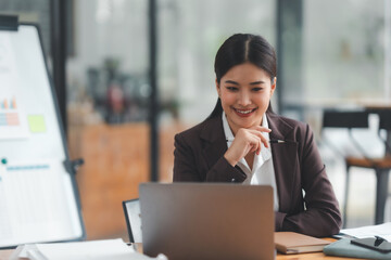 Asian businesswoman is sitting at a desk with a laptop in front of her