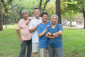 Asian elderly men and women Standing for photographers to take photos in the park before playing sports and exercising. Smile happily in retirement, take care of your health