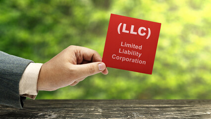 Business hand holding a note with LLC text, the acronym of Limited Liability Company