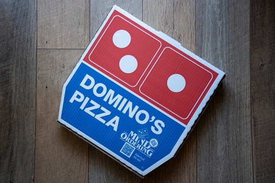 Portland, OR, USA - July 15, 2022: Top view of a Domino's Pizza box isolated on a wooden background. Domino's is an Ann Arbor-based American multinational pizza restaurant chain.