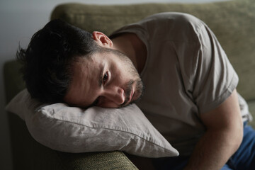 Close up of thoughtful man with head on pillow