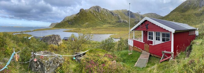 red wooden house in a meadow with sea views in peak mountain in Norway - nordland, vesteralen archipelago, Langoya island