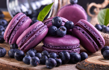 Purple macarons and blueberries on a wooden cutting board