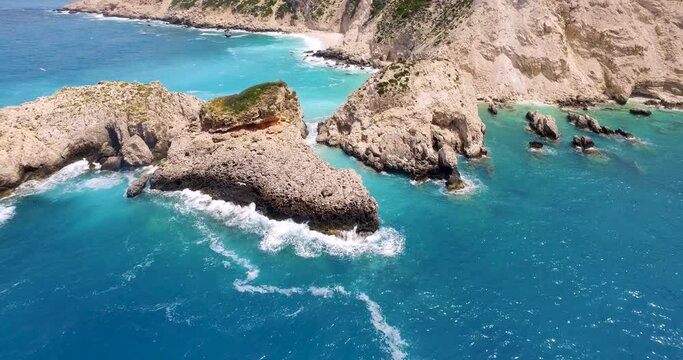 Orbiting drone shot of the boulders in the rocky shoreline of Petanoi Beach, located in the island of Kefalonia in Greece.
