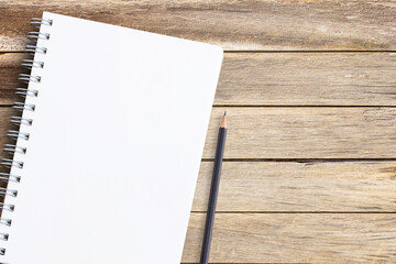 Top view with notebook and pencil on wooden table background,