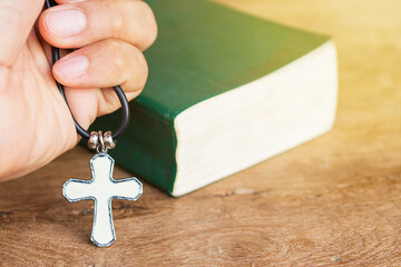  christian cross in hand with bible background