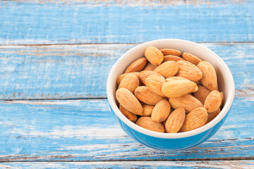 Almonds in a bowl on wooden table background.