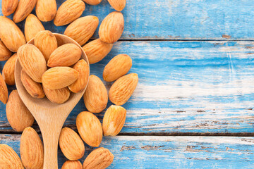 Peeled almonds in wooden spoon on wood background.