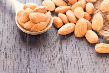 Peeled almonds in wooden spoon on wood background.