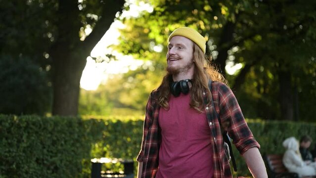 A young red-haired guy walks in the park in the evening, close-up, slow motion, backlight