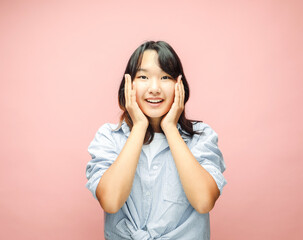 Cheerful Young asian woman amaze with shock deal, isolated on pink background