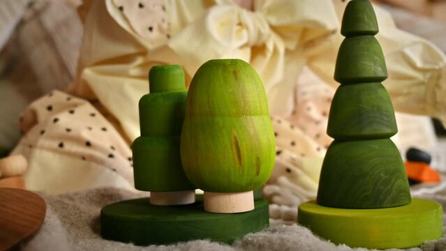 Little girl playing with several green wooden tree toys. Ecological and sustainability concept
