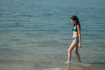 Fototapeta na wymiar relaxed young woman walking along the beach shore