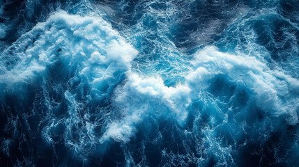 Fototapeta premium beautiful photo of blue water flowing in waves with white foam in a ocean. taken from up top above perspective. wallpaper background 