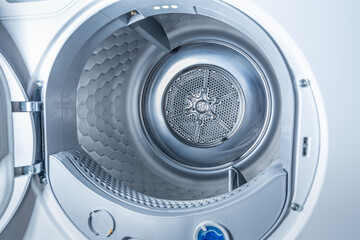 Inside of tumble dryer with clean laundry - new generation of heat pump dryer, household concept