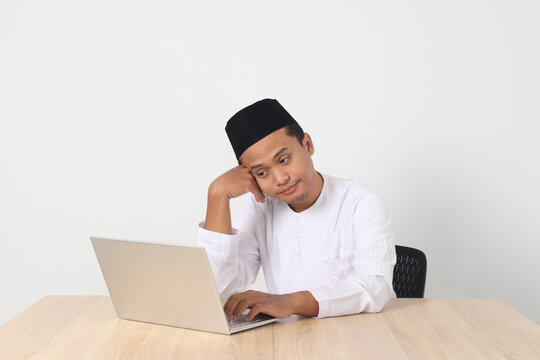Portrait of tired Asian muslim man in koko shirt with skullcap working during fasting on ramadan month, feeling sleepy, yawning with hand covering mouth. Isolated image on white background