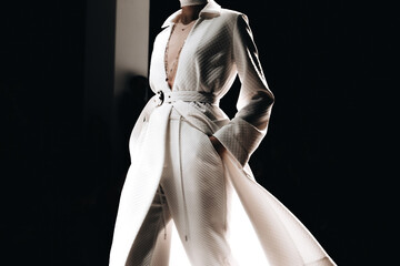 Fashion details of a stylish long white coat and pants. Women's Casual Fashion. SIde view