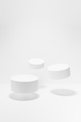 Abstract white scene mockup - three round tilt white cylinder podiums, soar in hard light, shadow. Template for presentation cosmetic products, goods, advertising, design, showing in spring style.