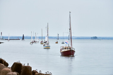 Parade of yachts along shore, several motor sailers yachts sailing along coast with lowered sails...