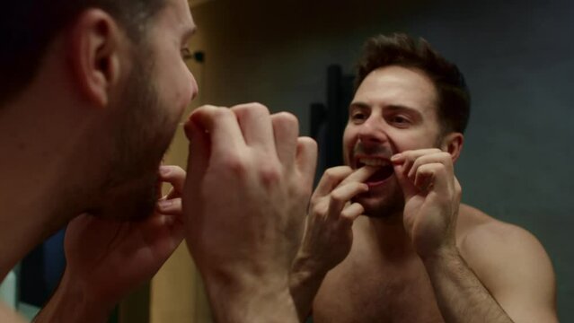 Man using dental floss in the domestic bathroom