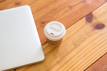 Top view of laptop computer and cup of coffee on wood table background.