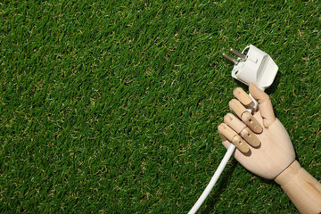 Electric cable in the hand of a mannequin on the grass