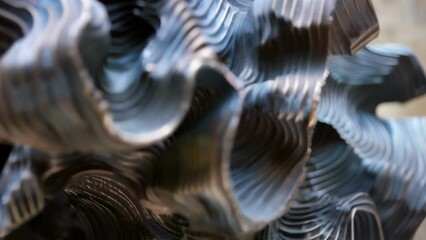 A closeup of a sculptures surface which is highly textured and seemingly in motion even though the piece is still. The organic patterns and ridges seem to cascade down the