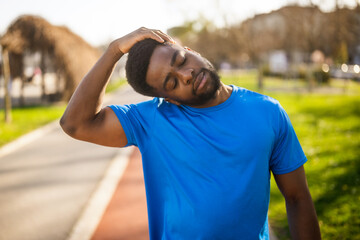 Young african-american man is exercising in the city. He is stretching his body.