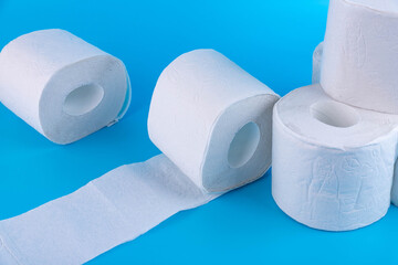 Rolls of white toilet paper on a blue background with place for text, advertising.