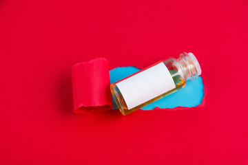 An ampoule of the COVID-19 coronavirus vaccine is a gift on a red background.