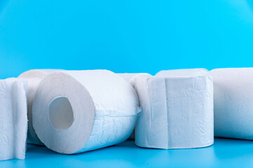 Rolls of white toilet paper on a blue background with place for text, advertising.