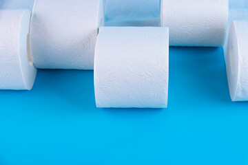 Rolls of white toilet paper on a blue background with place for text, advertising.