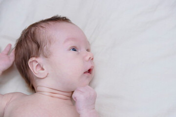 Little newborn boy lying in bed and emotion on his face.