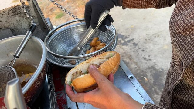 Overcooked bad food is bad for health and dangerous Cheap street food in Vietnam buy a bun. Vietnamese woman stuffing a bun with different ingredients to fry 