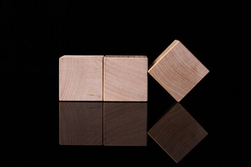 Three wooden cubes, blocks with empty space for copying words, messages, lie on a black reflective background. Business idea.