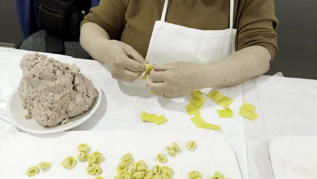 Woman pasta maker preparing artisanal tortellini. Production area Modena, Italy.
