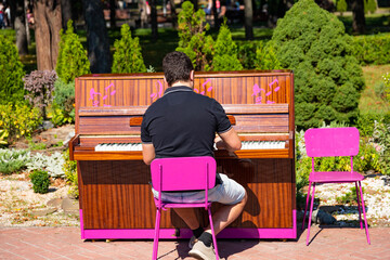 A man plays the piano on the street in the park. Street musician plays classical music on the piano...