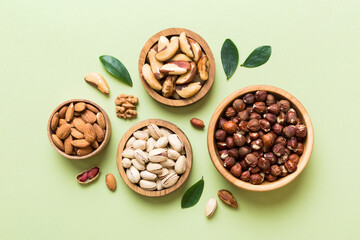 mixed nuts in wooden bowl. Mix of various nuts on colored background. pistachios, cashews, walnuts, hazelnuts, peanuts and brazil nuts