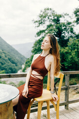 Portrait of a young brunette in a brown dress. sexy girl posing on the veranda in nature - 763057791