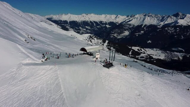 Mountain chairlift station with people getting off and hitting the slopes