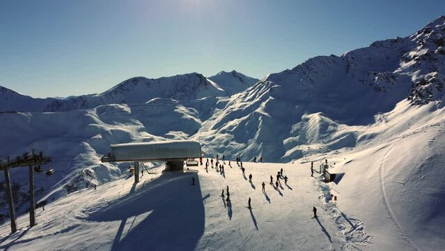 Sunny day at skilift with people in Austrian Alps mountains, aerial