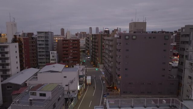 Forwards tracking of cyclist riding in streets of modern city. Multistorey apartment houses in residential urban neighborhood at Osaka, Japan