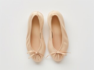 A pair of beige ballet shoes isolated on a white surface, top view, concept of dance and performance.