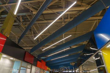 Beautiful ceiling and lighting design in a modern shopping mall. Wooden paneling on the ceiling and large round lamps.
