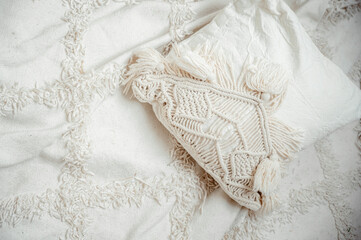 White macrame pillows and knit blanket on the sofa. Scandinavian cozy home, details interior