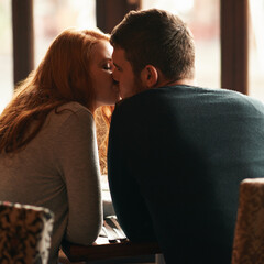 Couple, love and kiss on date at cafe for bonding, romance or healthy relationship with rear view....