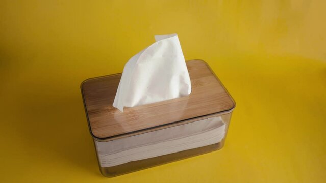 hand person take out tissue in container box with isolated yellow background