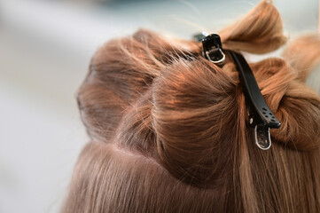 Detail of hair clips on a blonde client in a hair salon