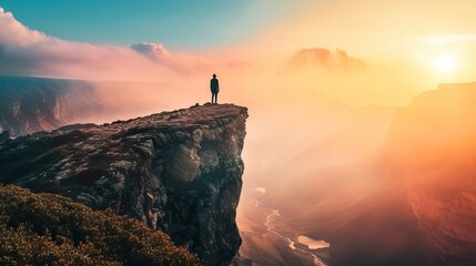 Person on cliff edge during a breathtaking sunrise with misty valleys below.